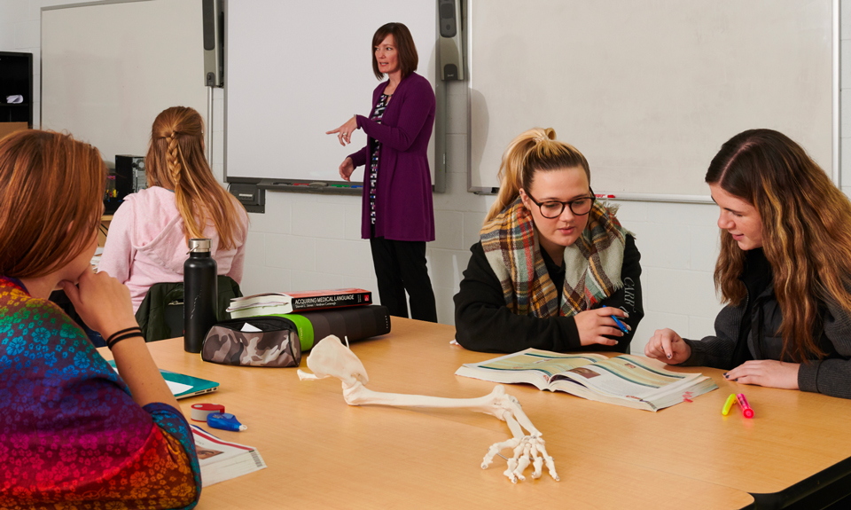 Rehabilitation Assistant students studing a skeleton mock-up.